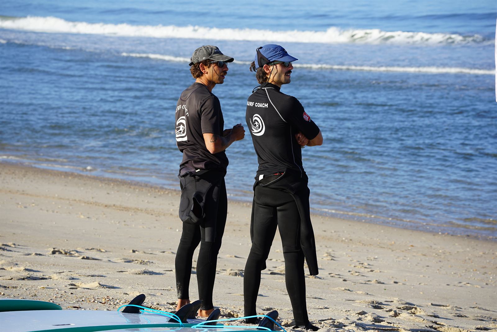 Dois instrutores da escola a observar o mar na praia