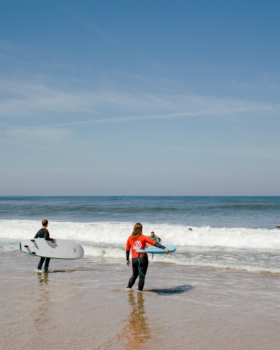 Alunos a entrar no mar com as pranchas